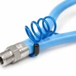 Tandoor Gas Hose AS01 – close-up of blue coiled restraining cable looped and zip-tied to the stainless steel male end fitting of the flexible tandoor gas hose, showing safety cable attachment method