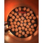 Tandoor Oven Clay Balls AS07 – straight overhead view of clay balls covering the full surface of a Morni-branded tandoor baffle plate inside a lit tandoor oven, with glowing orange clay walls surrounding the plate and the Morni logo glowing red through the heat