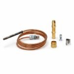Tandoor Oven Thermocouple AS12 – angled flat-lay of the complete thermocouple kit on white background showing the coiled copper capillary tube with steel probe tip at one end and compression fitting at the other, alongside the brass bullet-nose adaptor, brass hex nut fitting, steel clip, and small silver ferrule, all components included in the kit