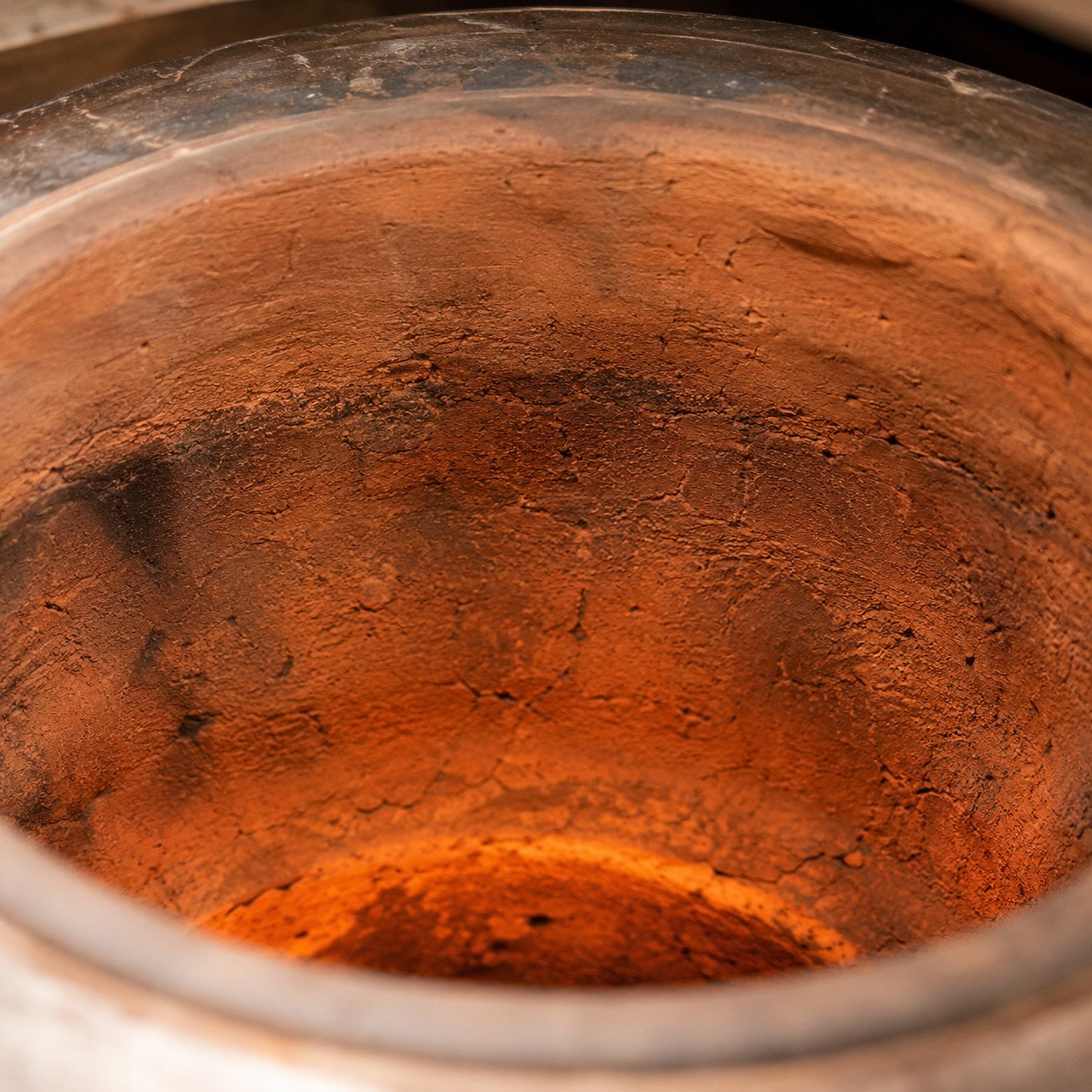 Close-up of a clay tandoor oven interior showing the traditional clay lining and insulation layer