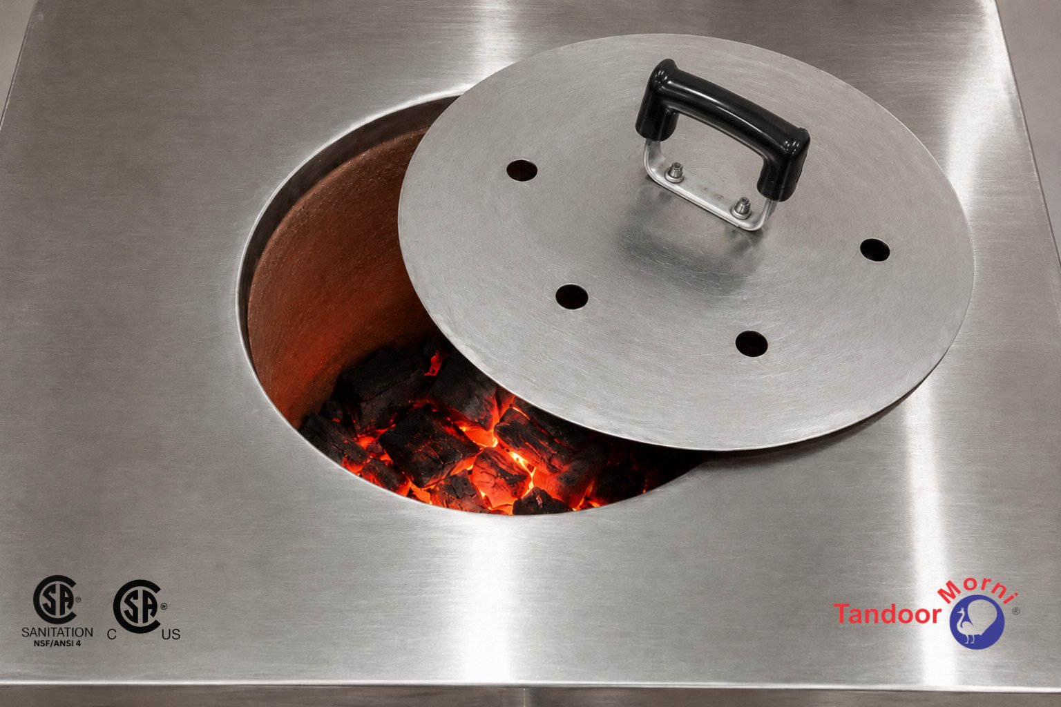Safe tandoor lid usage: a stainless steel tandoor oven lid held partially open while red coals glow inside the chamber
