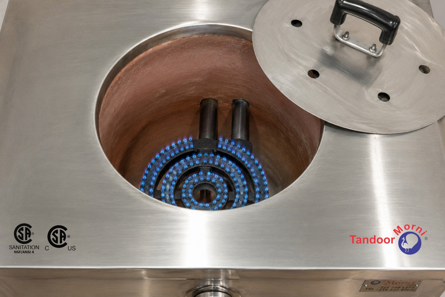 Lighting a commercial tandoor: a steady blue flame burning evenly inside a gas tandoor oven chamber during warm-up