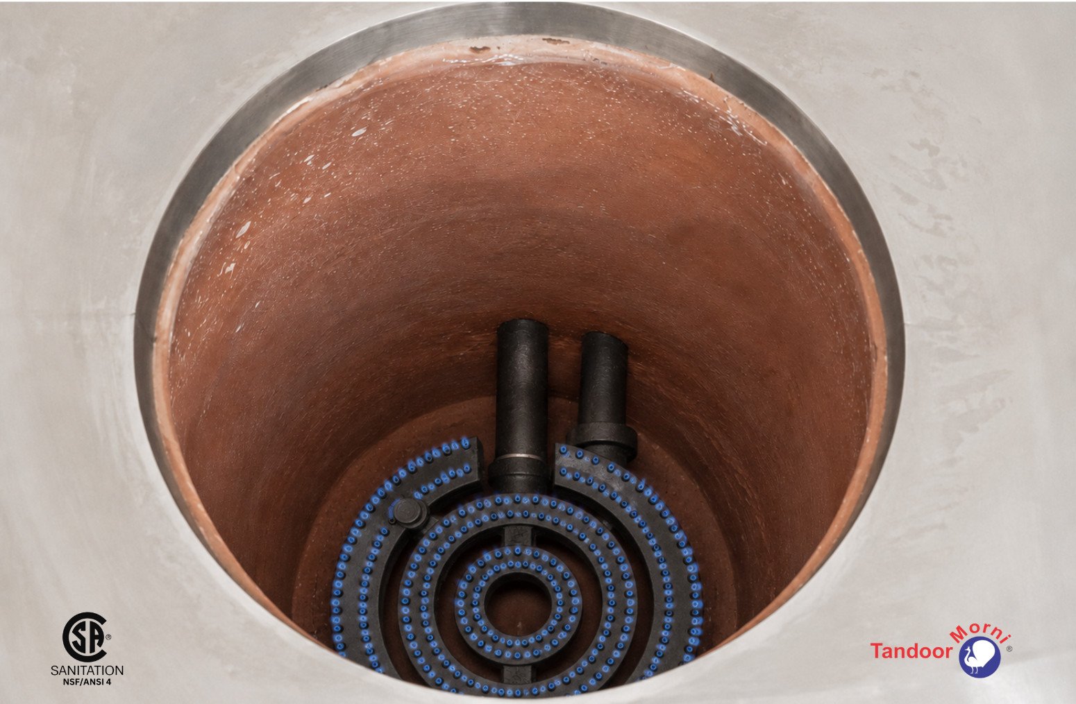 Gas tandoor oven burner glowing at the base of a commercial tandoor chamber, producing the steady heat behind the taste difference of tandoor cooking