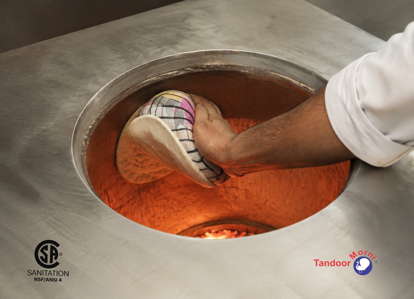 Naan bread tandoor oven recipe Step 5: chef pressing wetted dough onto the glowing wall of a tandoor using a naan gaddi