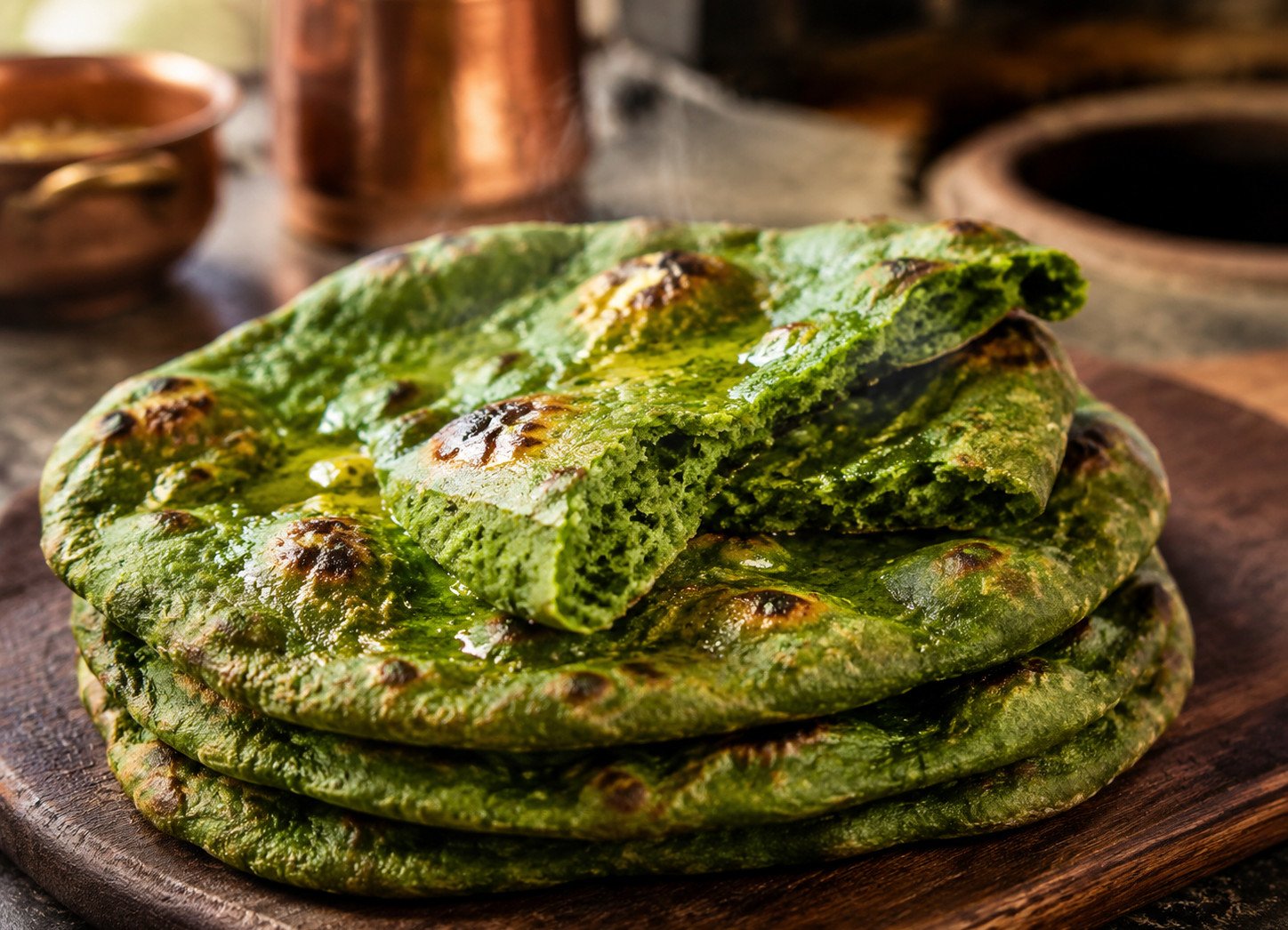 Spinach naan recipe fresh from the tandoor, deep green and blistered, stacked on a plate