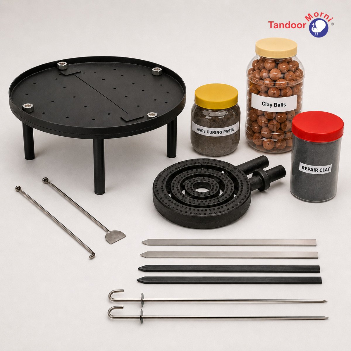 Tandoor oven accessories flat lay — Tandoor Baffle Plate AS02, Tandoori Naan Rod Pair AS03, Tandoor Skewers AS04, Tandoor Oven Curing Paste AS05, Tandoor Oven Burner AS06, and Tandoor Oven Clay Balls AS07
